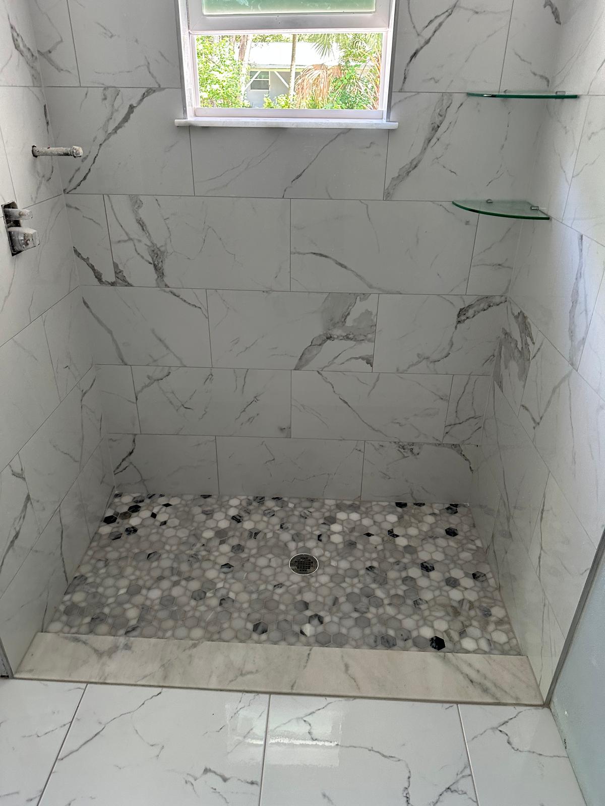 Calacatta porcelain shower with accent hex mosaic pan built by Ramirez Flooring in Tampa