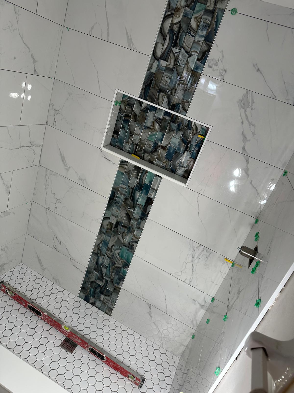 Precision tile work: blue agate glass band inset into Calacatta porcelain shower wall